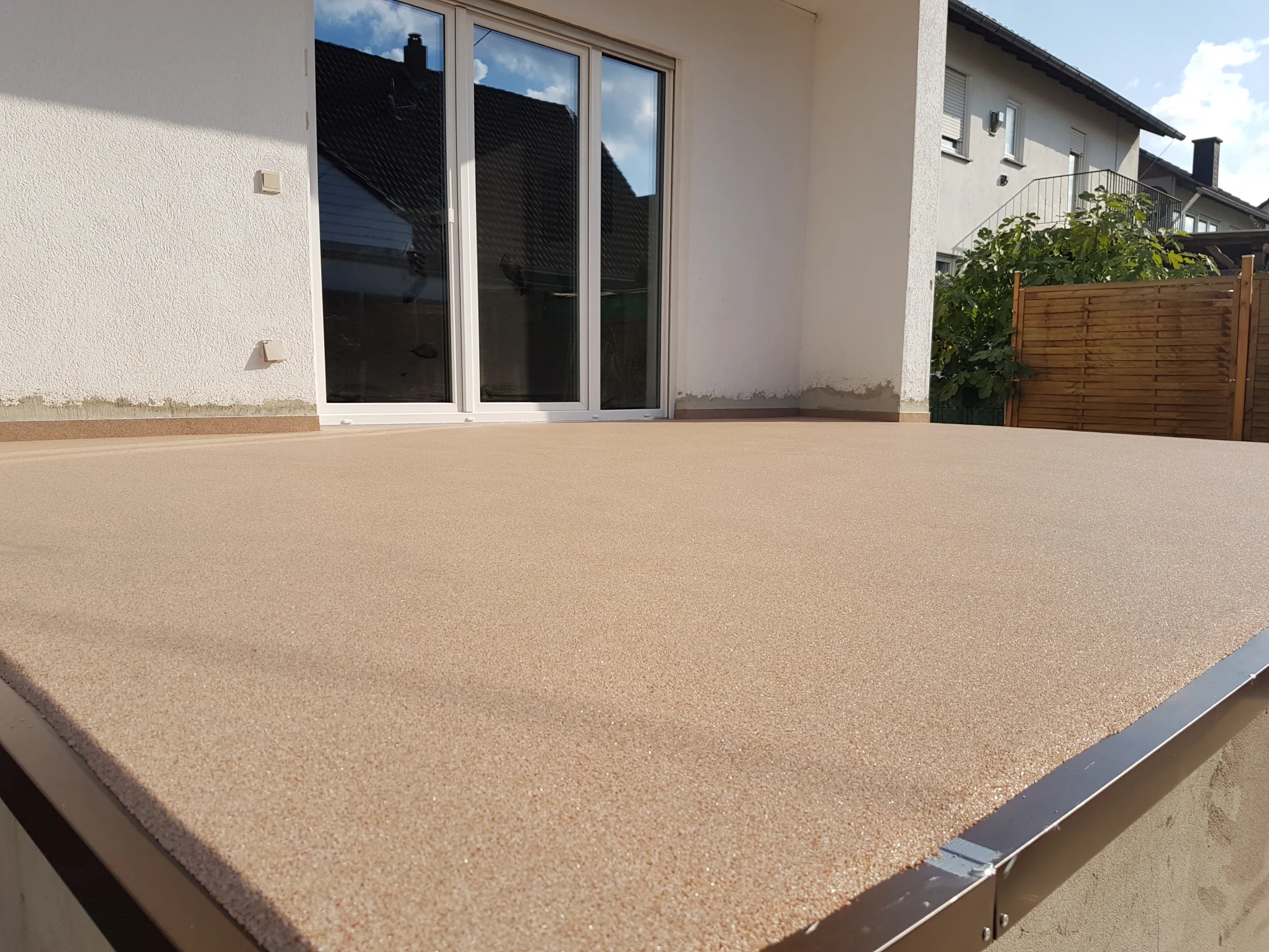 Beiger Steinteppich auf einem Balkon vor einer Terrassentür